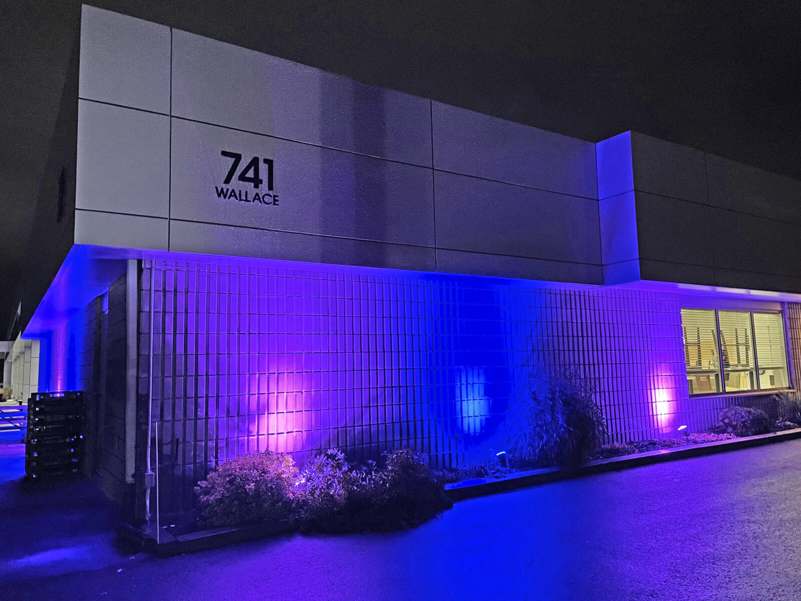 Exterior purple and blue lights shining on the front wall of the Community Living North Bay offices.