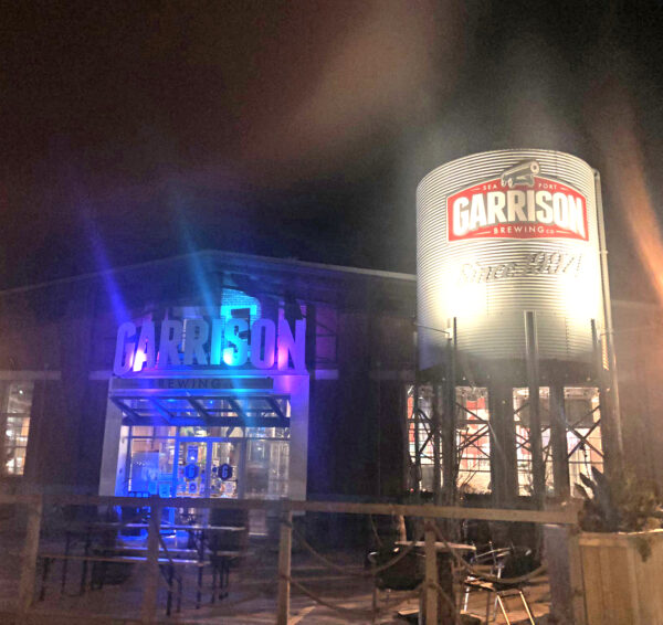 The sign on the Garrison Brewing Company, bathed in purple and blue light from spotlights.