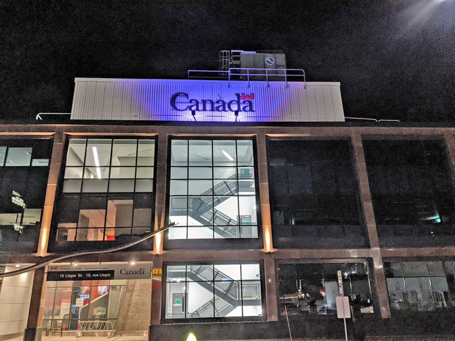 The "Canada" sign on the top of the federal government building in Sudbury, glowing purple.