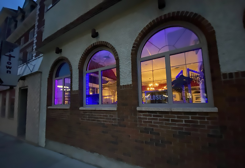 Window frames of a restaurant lit with strings of purple and blue lights.