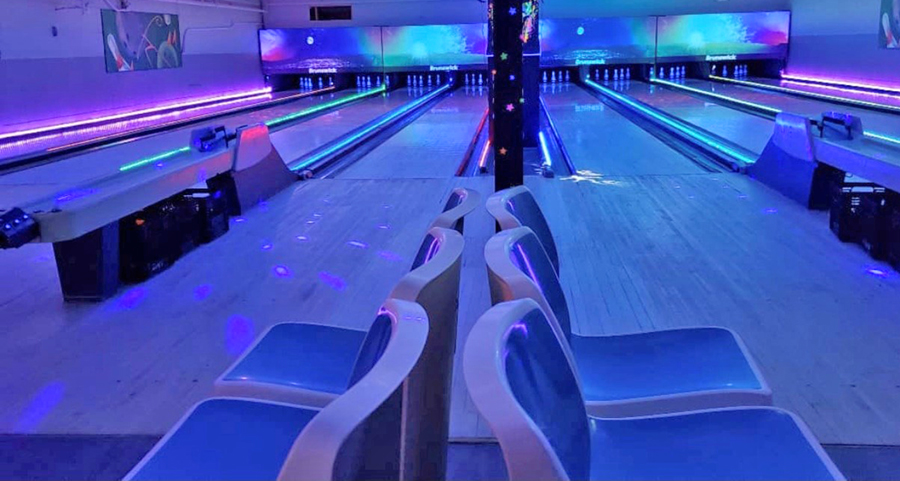 A bowling alley interior glowing with purple and blue ambient lighting