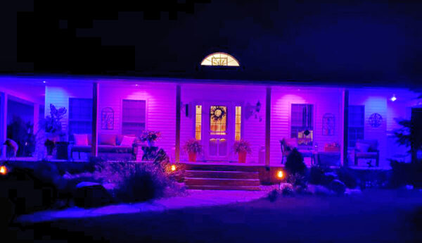 A frontal shot of a house porch glowing purple and blue.