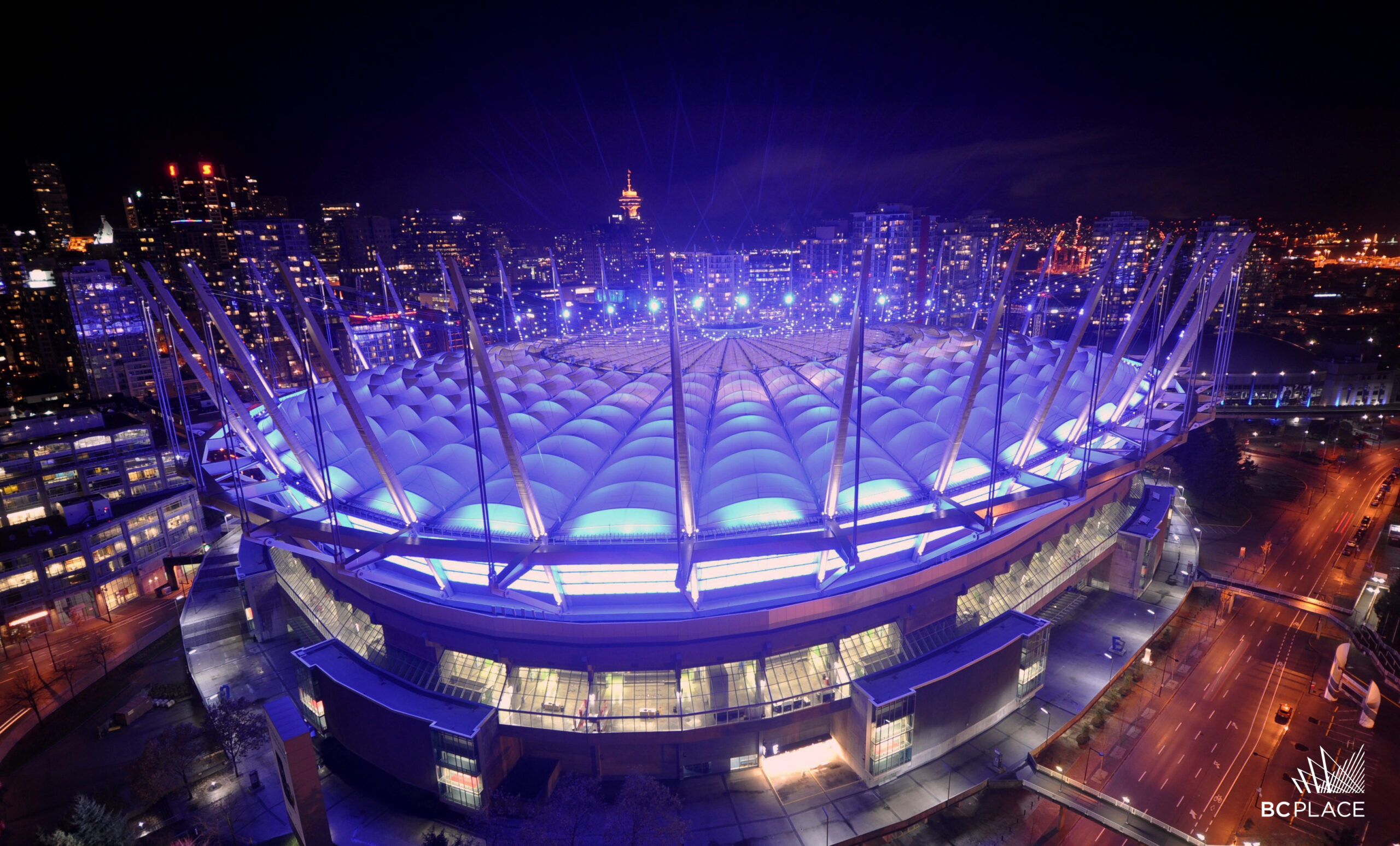 An aerial shot of BC Place in Vancouver lit purple and blue.